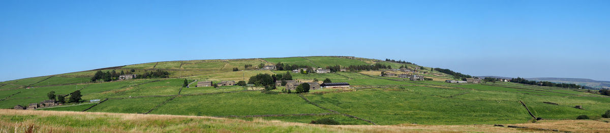 Scenic view of farm against clear blue sky