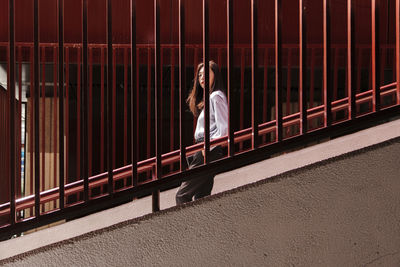 Portrait of woman standing against railing