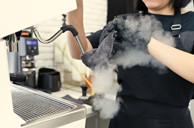 Midsection of woman preparing coffee at cafe