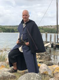 Portrait of man standing on rocks against lake