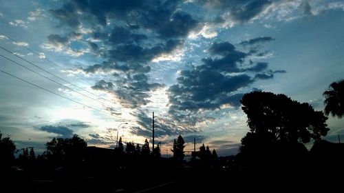 Low angle view of silhouette trees against cloudy sky