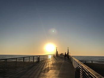 Pier over sea against sky during sunset