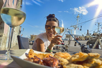 Young woman holding glass of drink on table