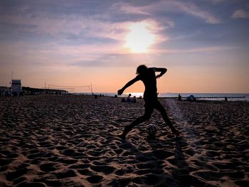 Silhouette man on beach against sky during sunset