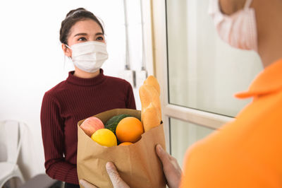 Midsection of couple holding orange