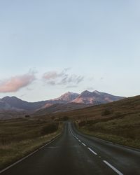 Road leading towards mountains against sky