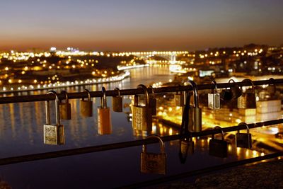 Close-up of illuminated bridge over river in city at night