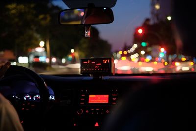 Illuminated city seen through windshield of car at night