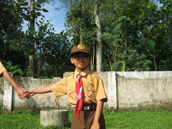 Portrait of smiling boy standing by trees against plants