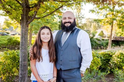 Portrait of happy friends and daughter standing against trees