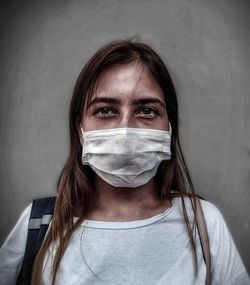 Portrait of woman wearing mask against wall