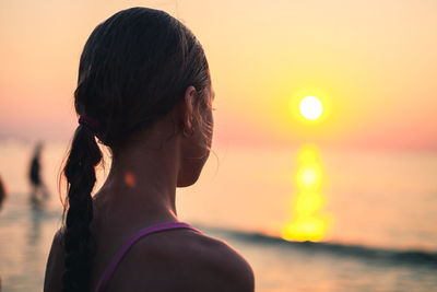 Girl looking at sea during sunset