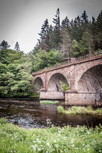 Arch bridge over river against sky
