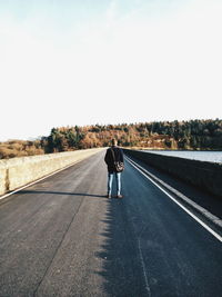 Rear view of person standing on road against sky