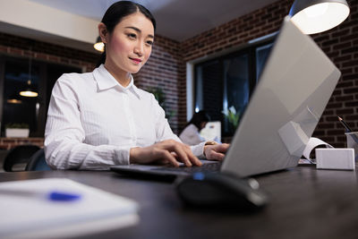 Businesswoman using laptop at desk in office