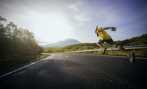 Man skateboarding on road against sky