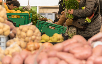 Midsection of woman picking vegetables at market stall