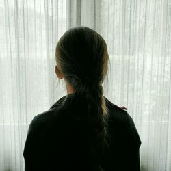 Rear view of woman standing against window