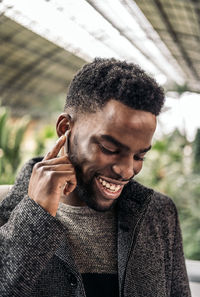 Close-up of smiling man talking on headphones while standing outdoors