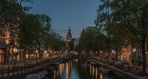 Illuminated rijksmuseum and canal in spiegelgracht against sky at night