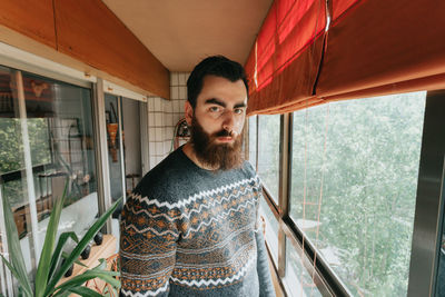 Portrait of young man looking through window