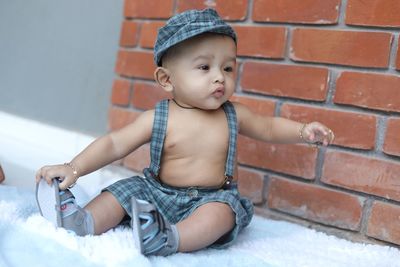 Cute baby girl sitting on brick wall