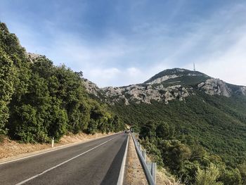 Road by mountains against sky