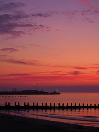 Pier over sea against romantic sky at sunset