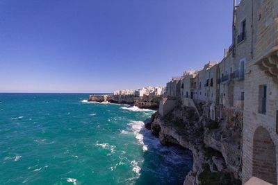 View of built structures along calm blue sea