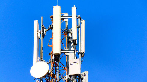 Low angle view of communications tower against clear blue sky