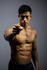 Shirtless muscular man standing against gray background