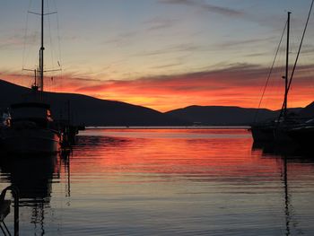 Silhouette boats moored on sea against orange sky