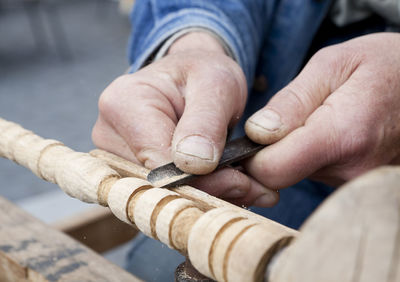 Cropped hands of carpenter carving wood at workshop