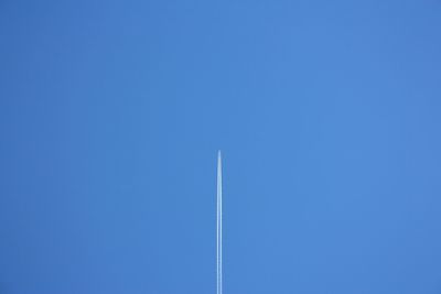 White trail of a plane far away in the blue sky landscape