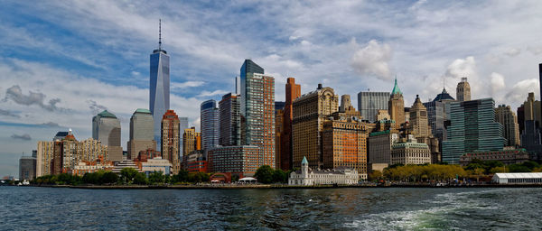 Modern buildings by river against sky in city