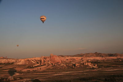 Hot air balloons flying over landscape against clear sky