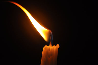 Close-up of lit candle against black background