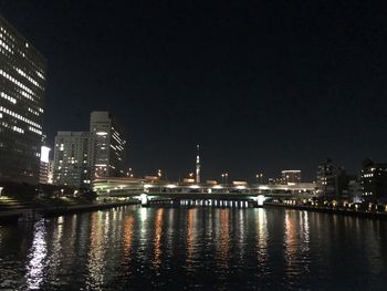 River by illuminated buildings against sky at night