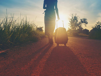 Low section of man walking on road against sky