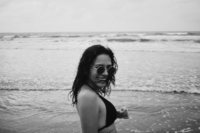 Portrait of smiling young woman in sunglasses beach against sky