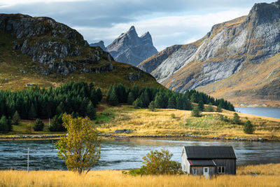 Scenic view of house by lake against mountains and sky