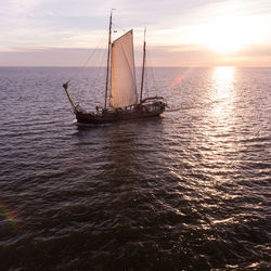 Sailboat sailing on sea against sky during sunset