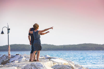 Rear view of woman standing by sea against clear sky