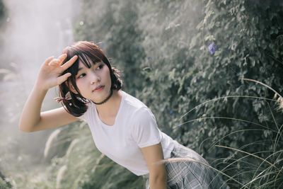 Beautiful young woman looking away while standing in forest