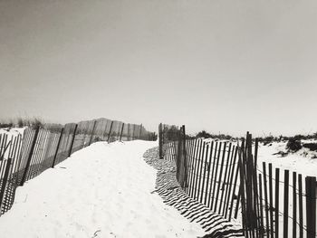 Fence on beach against clear sky