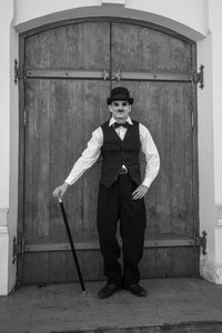 Full length portrait of young man standing against door