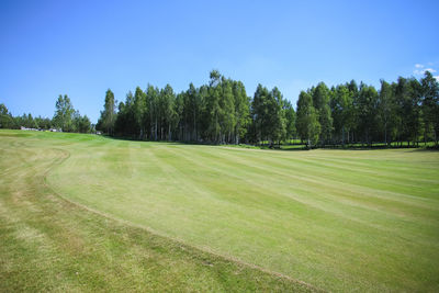 Scenic view of golf course against blue sky