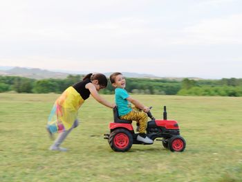 Side view of a boy with toy car on field