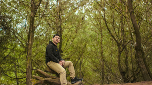 Young man sitting in forest