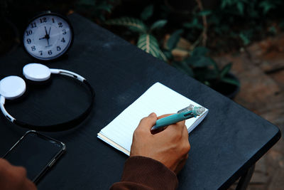 High angle view of man writing on note pad at table